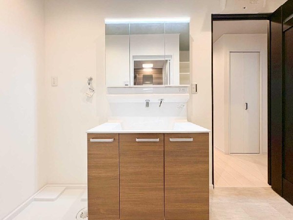 三面鏡収納やコンセント位置など、細かな使いやすさに配慮した洗面空間。木目パネルが落ち着いた雰囲気を演出し、毎日の身支度が快適に。