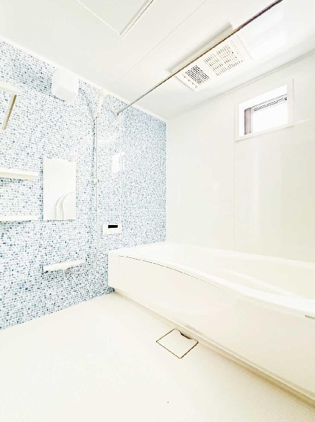 ブルー系アクセントパネルが爽やかな印象を与える浴室。窓付きで換気も良く、明るく清潔感のある空間です。浴室乾燥機を備え、雨の日の洗濯にも便利な使い勝手の良いバスルームです。