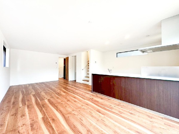 光と木目が美しく調和する開放的なLDK。天井まで広がる余白が心地よい、伸びやかなデザイン空間です。キッチンを中心にゆるやかにつながる住まい。