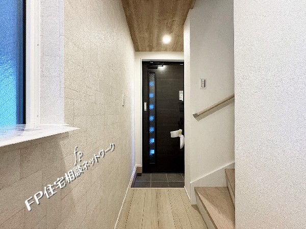 木目調の天井とやわらかな照明が、玄関にあたたかみを添える上質な空間。スタイリッシュなブラックドアが全体を引き締め、上品さと落ち着きを演出しています。