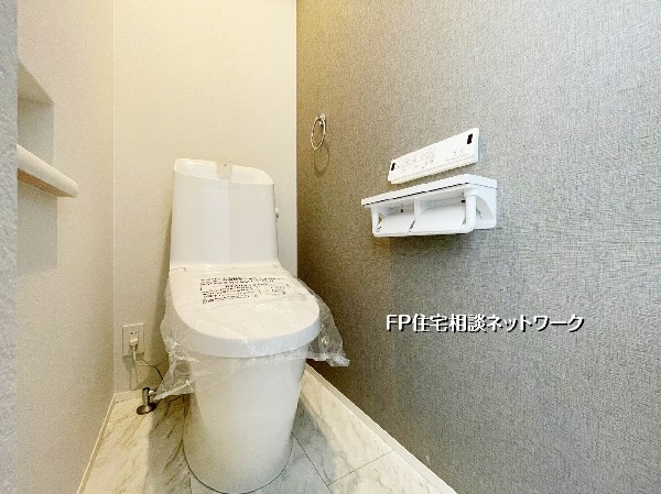 落ち着いたグレーのアクセントクロスが上質な雰囲気を演出。手洗い一体型で使い勝手も良好。清潔感あふれる明るいトイレ空間です。