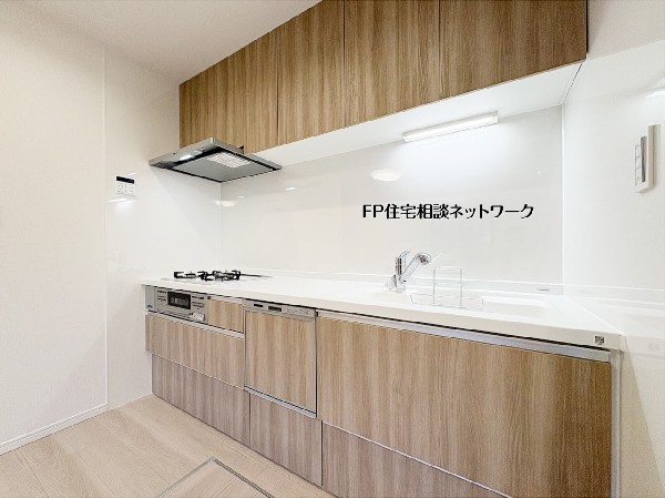 木目調の扉と純白のワークトップが調和した、ナチュラルで清潔感あふれるシステムキッチン。油汚れもサッと拭き取れるパネルを採用し、美しさを長く保てます。明るい空間で、毎日の料理が楽しくなる場所です。