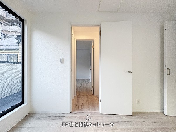 大きな窓から明るい光が差し込む居室。廊下へと続く開放的な間取りで、風通しの良い快適な空間です。