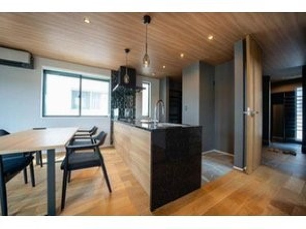 【建物プラン例　建物価格1980万円、建物面積100m2】木の温もりとブラックキッチンの洗練が融合。上質な素材感と落ち着いた照明が、心地よい大人の空間を演出します。