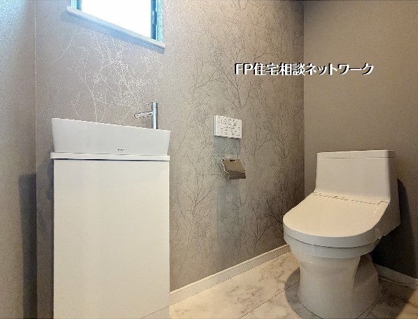 【トイレ】  清潔感のある白の設備に、木立を描いたアクセントクロスが映えるモダンなトイレ。大理石調の床が高級感を演出し、独立した手洗い器がゆとりある暮らしを叶えます。