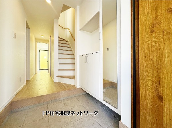 温かみある木目と白を基調とした明るい玄関ホール。大きな鏡付き収納で身支度もスムーズに。奥へと続く開放的な動線が、帰宅時に心地よいひとときを演出します。