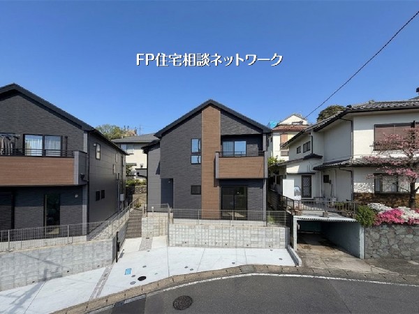 外観:モダンな黒の外壁に木目調のアクセントが映える、スタイリッシュな新築戸建が登場。周囲は落ち着いた住宅街で、青空に映える美しい外観が魅力です。