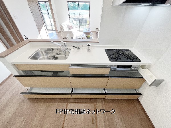 【キッチン収納】  対面式キッチンは白基調で清潔感たっぷり。食洗機・三口コンロ付きで家事効率◎。広々ワークトップと豊富な収納で、家族との会話も弾む快適な空間です。