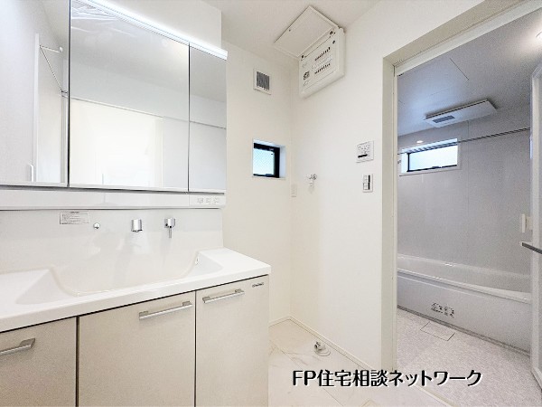 【洗面脱衣室】  白を基調とした清潔感溢れるサニタリー。機能的な三面鏡付き洗面台や、ゆったり寛げる浴室を完備。毎日の身支度やバスタイムを、明るく快適な空間で心地よく過ごせる機能的な設計が魅力です。