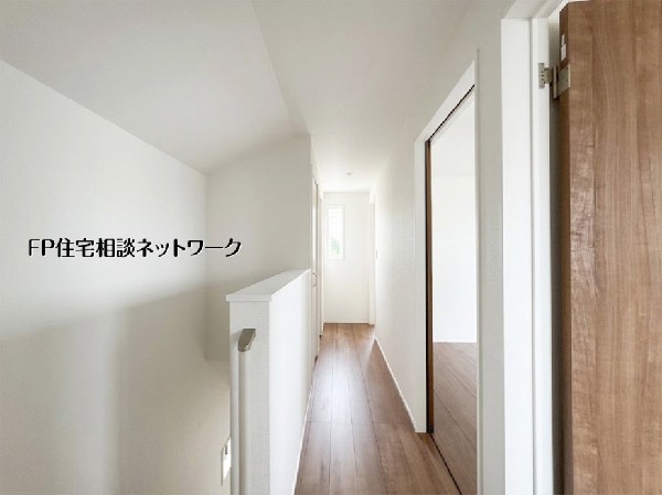 【2階廊下】  白を基調とした壁と温かみのある木目調の床が、心地よい空間を演出する2階廊下。奥の窓から差し込む自然光が足元を明るく照らし、住まい全体に開放感を与えます。