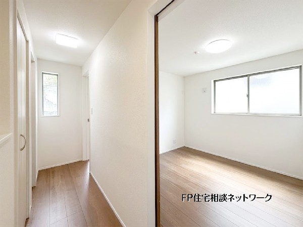 【2階廊下】  廊下にも窓を配置し、住まい全体に自然光が届く設計。白を基調とした清潔感のある内装と木目調の床が、穏やかな空間を創り出します。