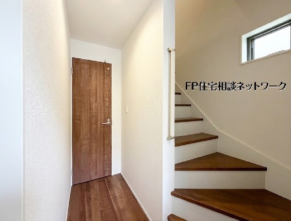 【玄関ホール】  木のぬくもりが優しく出迎える、落ち着いた雰囲気の玄関ホール。階段横に窓を配置することで、暗くなりがちな空間に自然光を採り入れました。