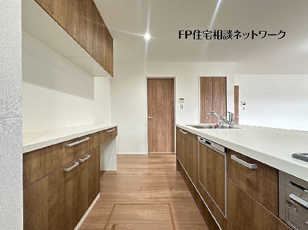 【キッチン】木目調のパネルが上品なシステムキッチン。広々としたワークトップと3口コンロ、食洗機を完備し、日々の料理や片付けがスムーズに捗ります。