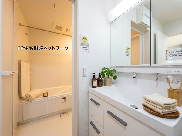 【洗面脱衣室】  清潔感あふれる白を基調とした、洗面室とバスルームです。三面鏡付きの洗面化粧台は収納力も高く、機能的で使いやすい設計。毎日の身支度やバスタイムを快適に過ごせる空間です。