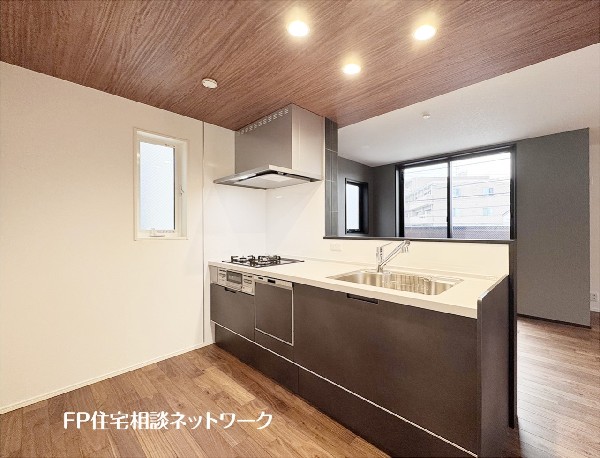 【キッチン】  木目調のアクセント天井とシックな黒のシステムキッチンが調和する、スタイリッシュな対面式空間です。便利な食洗機やコンロ横の窓も魅力。