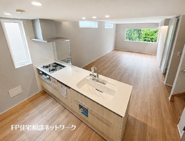 【LDK│20帖】  家族の会話が弾む、開放感あふれる対面式キッチンを備えたLDKです。窓から自然光がたっぷりと降り注ぎ、木の温もりを感じるフローリングが心地よい、明るく快適な団らん空間です。