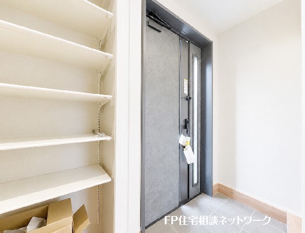 【玄関│シューズインクローゼット】  モダンで重厚感のある玄関ドアがお出迎えします。壁一面に設けられた大容量のシューズボックスは便利な可動棚となっており、家族全員の靴をすっきりと整理整頓できます。