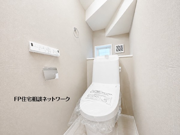 【トイレ】  階段下を活用した清潔感あふれるトイレです。小窓から自然光が差し込み、明るく落ち着ける空間を保てます。使いやすい壁付けリモコンを備え、毎日快適にお使いいただける実用的な設計です