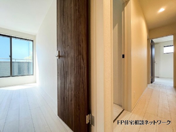 【2階廊下】  明るく清潔感のある2階廊下。白を基調とした内装に、木目調のドアが温かみのあるアクセントを添えています。各部屋への動線がスムーズで、奥の窓からは心地よい光が差し込みます。