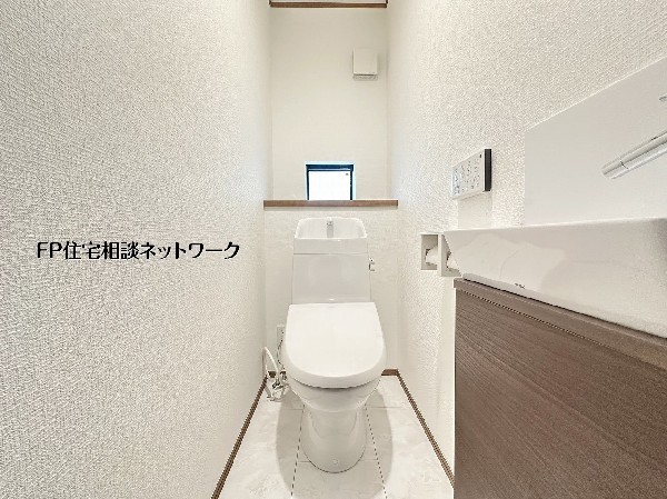 【トイレ】白を基調とした清潔感あふれるトイレ。独立した手洗い場を備え、使い勝手と衛生面を両立しました。小窓から入る自然光が空間を明るく保ち、木目調のアクセントが落ち着いた雰囲気を醸し出す、心地よいプ 