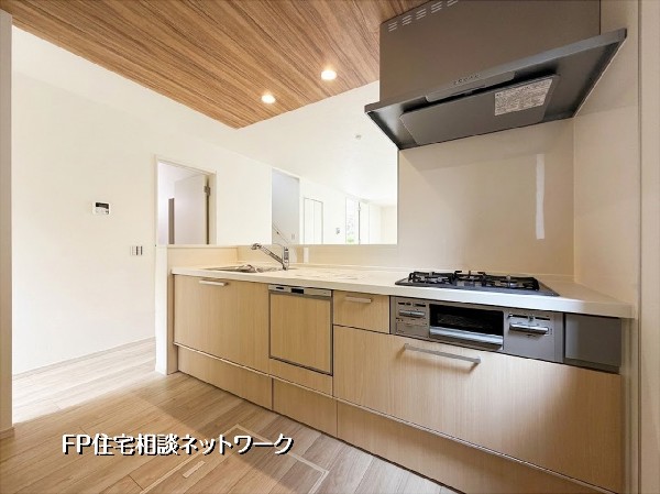 【キッチン】木目調の天井が印象的な、温かみのある対面式キッチンです。食洗機や3口コンロなど、家事を支える設備が充実。リビングを見渡しながら料理を楽しめる開放的な設計で、家族との会話も自然と弾みます。