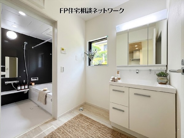【洗面脱衣室】清潔感あふれる洗面室とシックなバスルームが隣接し、日々の疲れを癒やす空間です。三面鏡タイプの洗面台は収納力があり、小窓からの採光で明るさも確保。