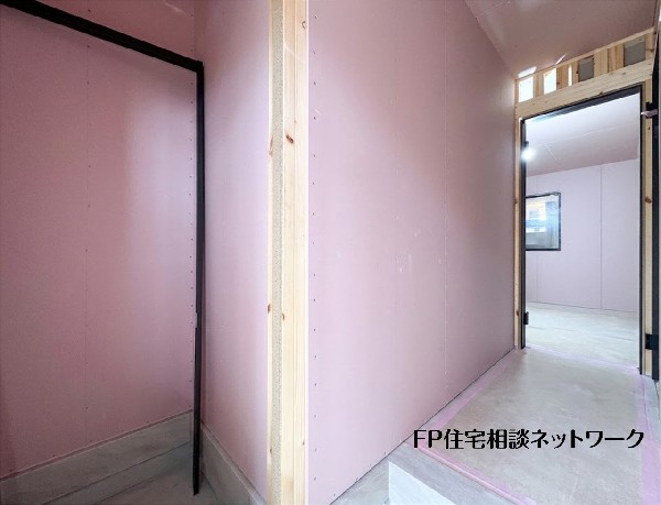 【シューズインクローゼット】  玄関から奥の部屋へと続く廊下部分の建築風景です。壁の下地施工が進み、黒い建具枠が設置されました。木の柱や骨組みも確認でき、室内の間取りが明確に形作られてきています。