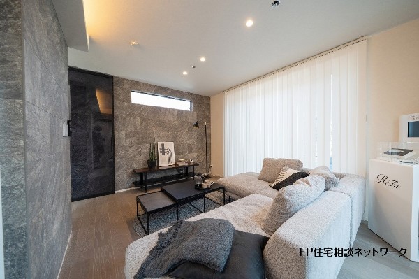【プラン例　建物価格2400万円　建物面積100m2】石目調のアクセントウォールが印象的なリビング。落ち着いた色合いでまとめ、ゆったりくつろげる空間に仕上げました。