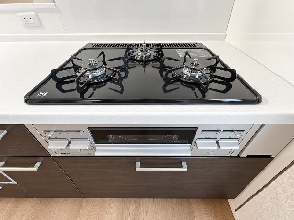 【三口ガスコンロ】同時に異なる料理を作ることができ、調理時間を大幅に短縮できる便利な調理器具です。様々なサイズの鍋に対応し、効率的な調理をサポートします。     換気扇  その他設備   ステンレスの鈍い輝きが高級感を醸し出す換気扇。従来タイプよりも換気効果に優れ、フィルター交換もお掃除も容易になりました。   