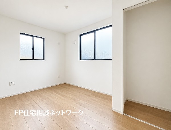 【洋室】  二面の窓から光を取り込める、明るく風通しの良い洋室です。荷物を整理できる収納スペースも確保されています。シンプルな内装で落ち着いた空間となっています。
