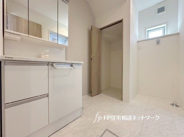 収納力のある三面鏡タイプの洗面化粧台に加えてリネン庫もあります。キッチン近くに水回り集中し家事動線良好。